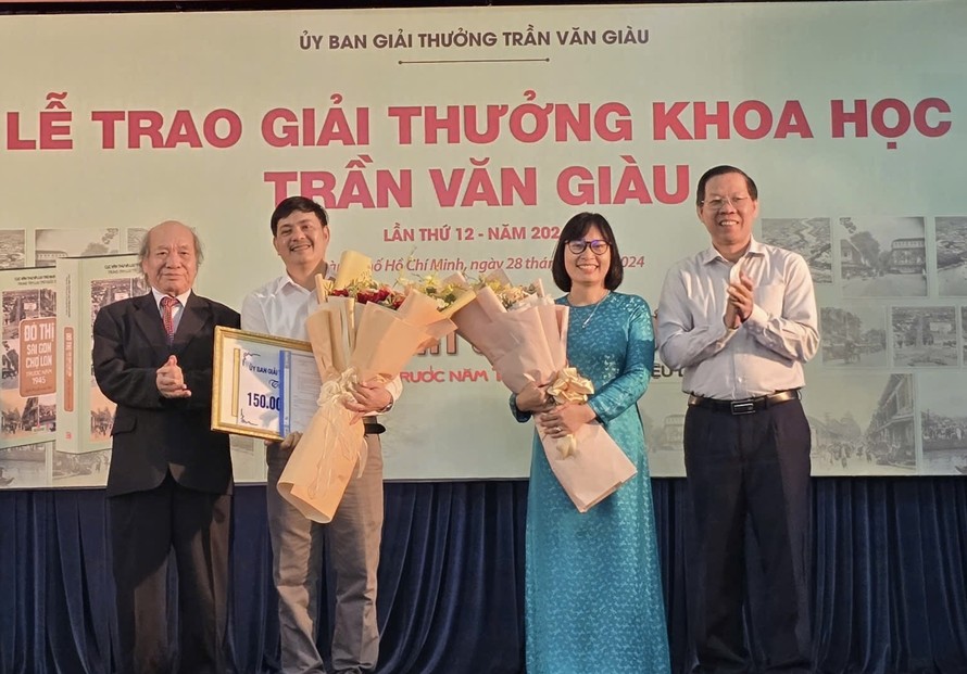 Ông Phan Văn Mãi (bìa phải), Chủ tịch UBND TPHCM và GS.TS Ngô Văn Lệ, Phó chủ tịch thường trực Ủy ban Giải thưởng Trần Văn Giàu trao giải thưởng và tặng hoa chúc mừng hai tác giả đoạt giải