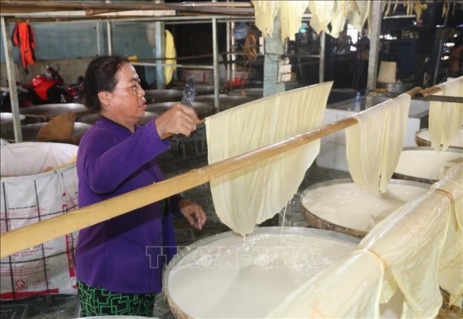 Người thợ đưa lá tàu hũ ky lên giàn phơi.