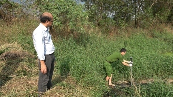 Cán bộ Phòng Cảnh sát Môi trường lấy mẫu nước thải giám định. Ảnh: Báo Công an Nhân dân