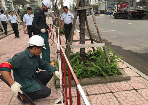 Lực lượng chức năng phá dỡ rào chắn bằng sắt dựng trên vỉa hè chung cư Vinaconex 7. Ảnh: Gia Chính.