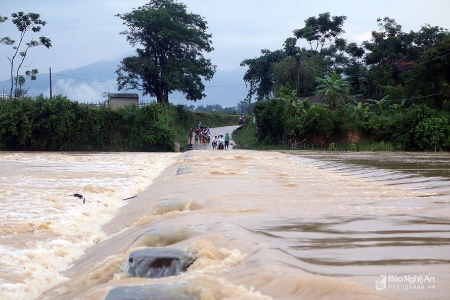 Sau những cơn mưa to, đập tràn cạnh bản Hoa Tiến 1 biến thành dòng sông lớn, nước chảy cuồn cuộn gây trở ngại cho người và phương tiện qua lại. Mỗi ngày, cư dân ở hai bản Hoa Tiến 1 và Hoa Tiến 2 với tổng cộng 371 hộ phải qua lại trên con đập này. Ảnh: Hữ