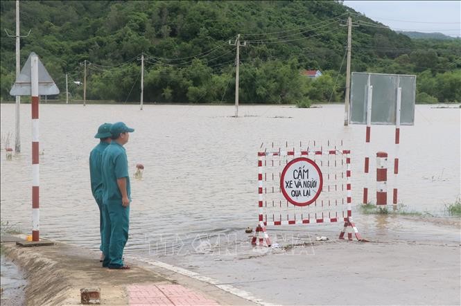 Lực lượng chức năng trực chốt tại khu vực cấm người dân qua tuyến đường DT642 thị trấn La Hai, huyện Đồng Xuân (Phú Yên) bị ngập do nước lũ. Ảnh: Phạm Cường/TTXVN