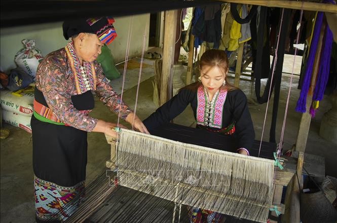 Phụ nữ dân tộc Lào truyền dạy nghề dệt vải thổ cẩm cho thế hệ trẻ. 