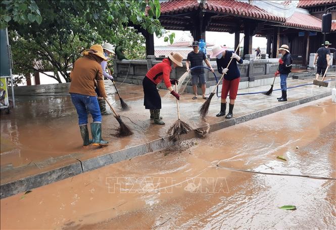 Người dân vệ sinh môi trường sau lũ lụt, phòng dịch bệnh. Ảnh: TTXVN