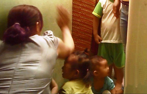 1 bảo mẫu dùng tay đánh 2 cháu bé. Ảnh: Tuổi Trẻ