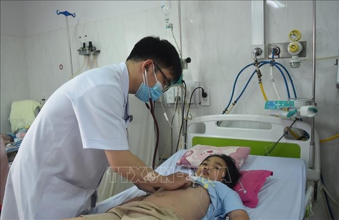 Bác sỹ thăm, khám cho bệnh nhi bị sốt xuất huyết nặng. Ảnh: Nguyên Dung/ TTXVN.