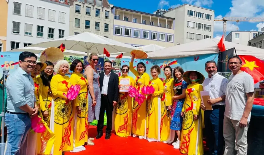 Bà Eva Weber (váy xanh nhạt) - Thị trưởng thành phố Augsburg và ông Phạm Huy Phương (áo vest đen) - Trưởng ban Công tác Cộng đồng Đại sứ quán Việt Nam tại Đức chụp ảnh lưu niệm với cộng đồng người Việt tại thành phố Augsburg.