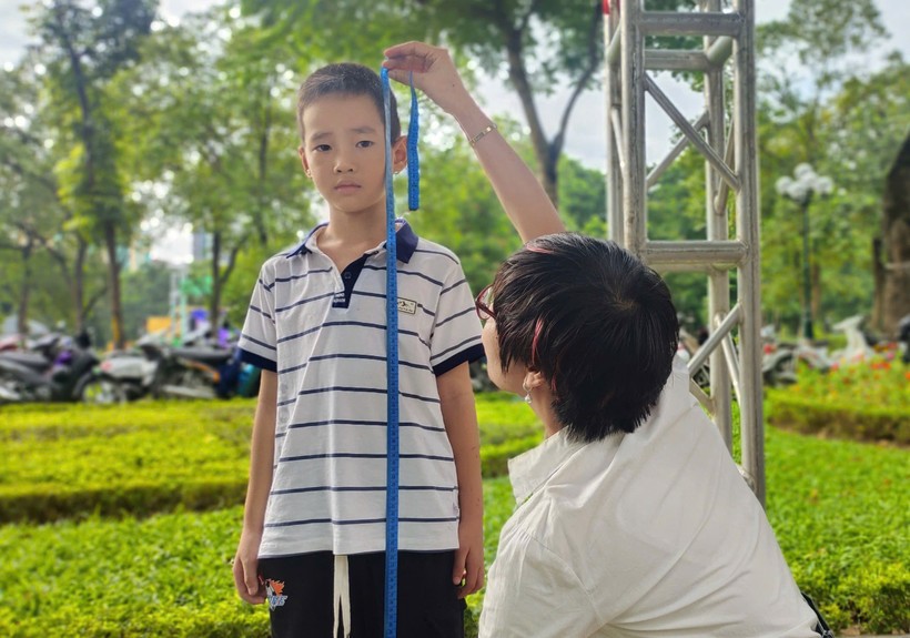 Nhân viên y tế đo chiều cao cho trẻ tại ngày hội.
