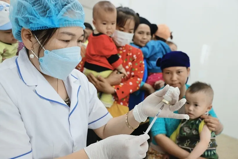 Người dân đưa trẻ đến tiêm chủng. Ảnh: Minh Quyết/TTXVN