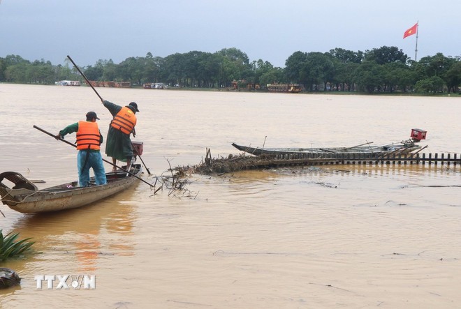 Công nhân dọn rác do lũ cuốn dạt vào bờ Nam sông Hương, thành phố Huế sáng 2/11. Ảnh: Nguyên Lý /TTXVN.