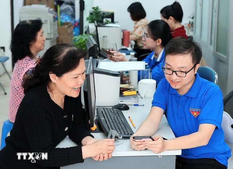 Đoàn viên thanh niên phường Hàng Bồ (quận Hoàn Kiếm, thành phố Hà Nội) hỗ trợ người dân thực hiện thủ tục hành chính công trên thiết bị điện thoại thông minh. Ảnh: Phạm Hậu/TTXVN.