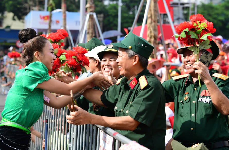 Các cựu chiến binh khoác tấm áo lính vẫy cờ, trao hoa cho các chiến sĩ trẻ.
