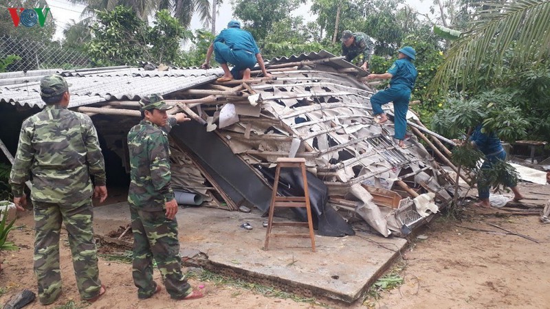 Các cán bộ, chiến sỹ cùng người dân dựng lại nhà cửa sau cơn bão.