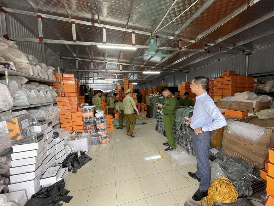 Lực lượng chức năng kiểm tra kho hàng chứa hàng giả. Ảnh: QL/TTXVN