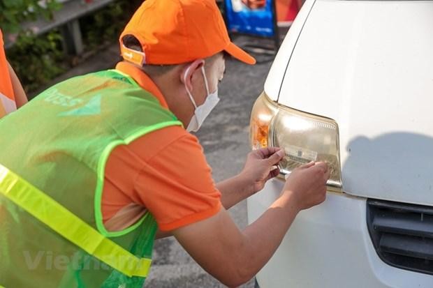 Nhân viên của Công ty cổ phần Giao thông số Việt Nam (VDTC) dán thẻ thu phí không dừng cho phương tiện. (Ảnh: Minh Sơn/Vietnam+) 