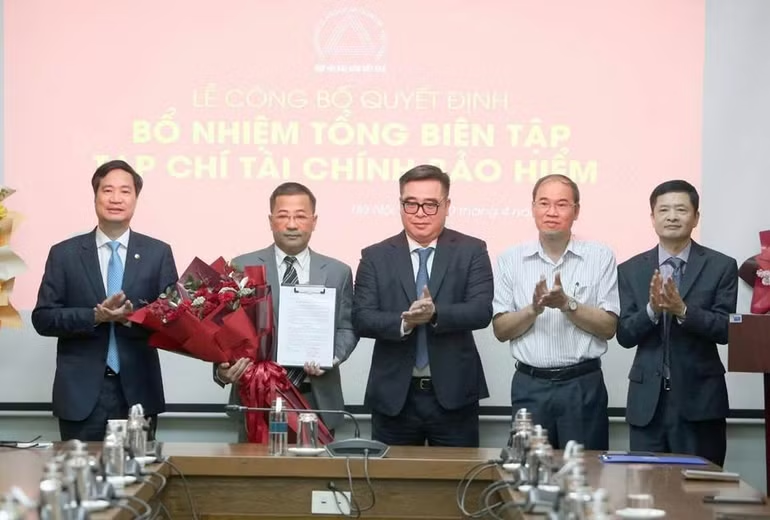 Cục trưởng Cục Quản lý, Giám sát Bảo hiểm Ngô Việt Trung, Phó Cục Trưởng Cục Quản lý, Giám sát Bảo hiểm Phạm Văn Đức, Chủ tịch Hiệp hội Bảo hiểm Việt Nam Nguyễn Xuân Việt và Tổng Thư ký Hiệp hội Bảo hiểm Việt Nam Phạm Ngọc Sơn, tặng hoa chúc mừng nhà báo Nguyễn Phong Cầm. (Ảnh: Tuấn Minh)