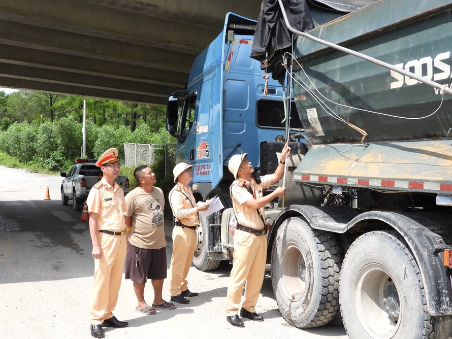Lực lượng CSGT tiến hành đo chiều cao thành thùng của phương tiện vận tải tại lối ra vào khu vực mỏ đá trong ngày đầu ra quân. (Ảnh: Hoàng Anh)
