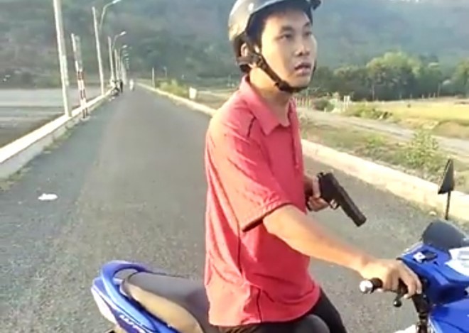 Ông Mai Thanh Tuấn dùng một vật giống khẩu súng đe dọa người dân. Ảnh cắt từ clip.