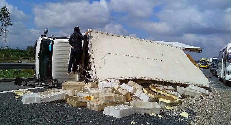 Chiếc xe lật nhào chắn ngang đường. Ảnh: CAND