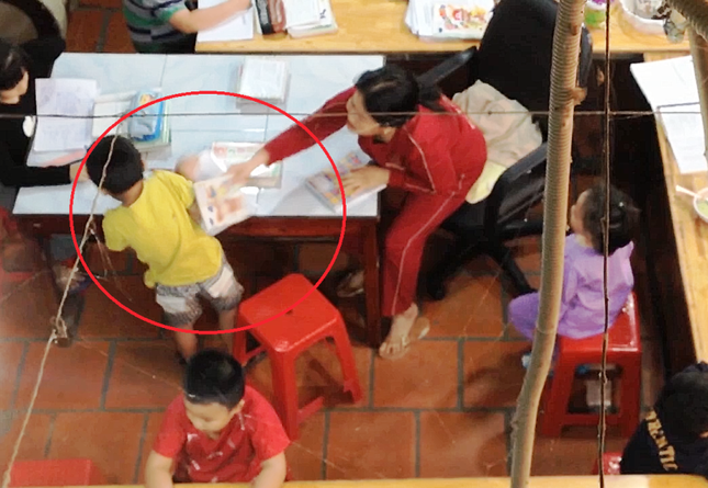 Một em học sinh bị người phụ nữ dùng vỡ đánh vào vai. - Ảnh cắt từ clip.