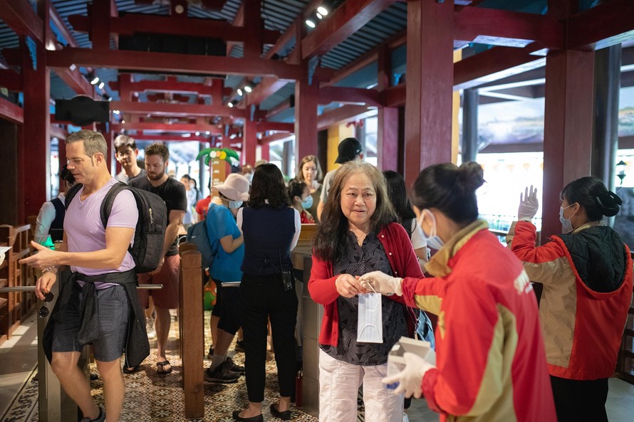 Nhân viên tại Bà Nà Hills phát khẩu trang miễn phí và hướng dẫn du khách đeo khẩu trang đúng cách