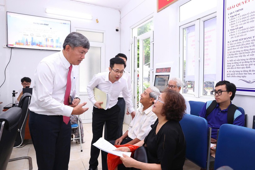 Chủ tịch Ủy ban Nhân dân phường Hồng Hà trao đổi với người dân đến làm thủ tục hành chính tại Điểm số 1-Khu vực Tứ Liên. Ảnh: Xuân Quảng/Vietnam+