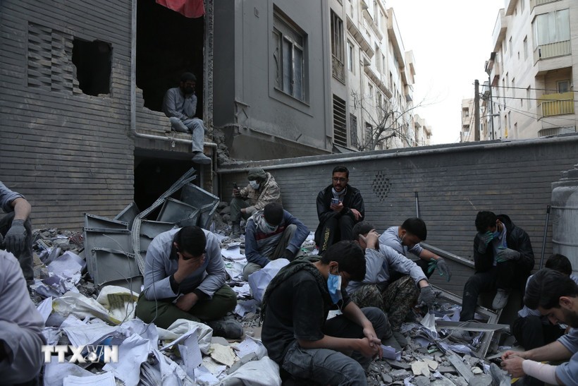Người dân ngồi trên đống đổ nát của những tòa nhà bị phá hủy do xung đột tại Tehran, Iran ngày 15/3/2026. Ảnh: THX/TTXVN