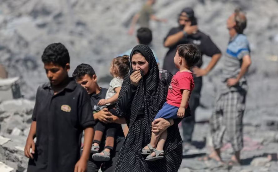 Người dân Palestine đứng trên đống đổ nát sau các cuộc không kích của Israel xuống Dải Gaza. 