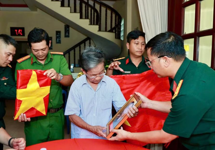 Ông Phan Văn Tư xúc động bên di ảnh hai người anh trai đã hy sinh. (Ảnh: Bộ Tư lệnh Thành phố Hồ Chí Minh cung cấp)