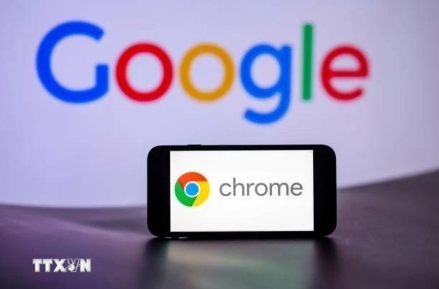 Biểu tượng Chrome trên màn hình điện thoại và biểu tượng Google (phía sau). Ảnh: Getty Images/TTXVN