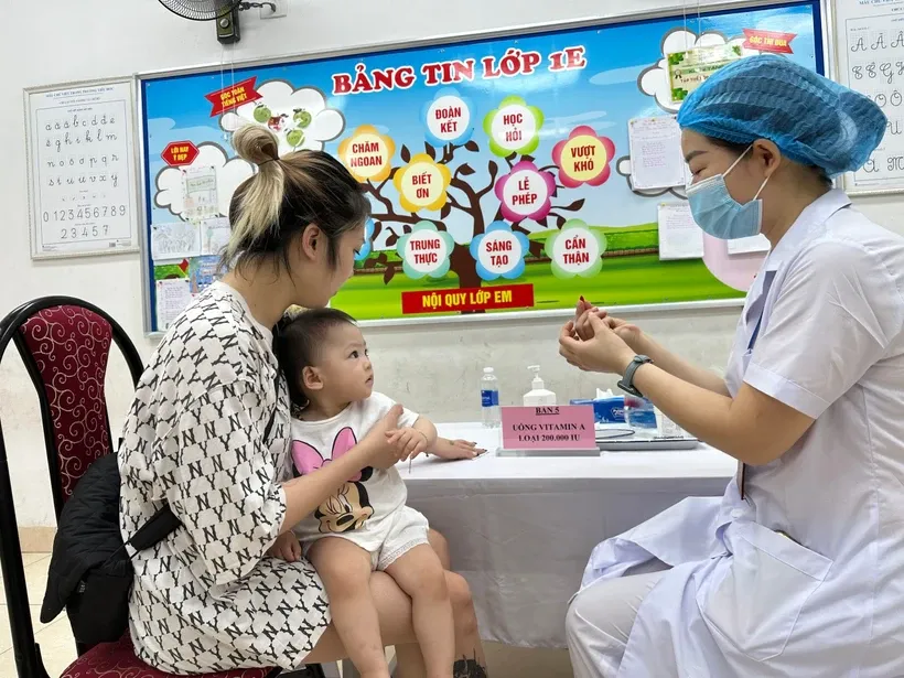 Phụ huynh cho trẻ đến trạm y tế để bổ sung Vitamin A.