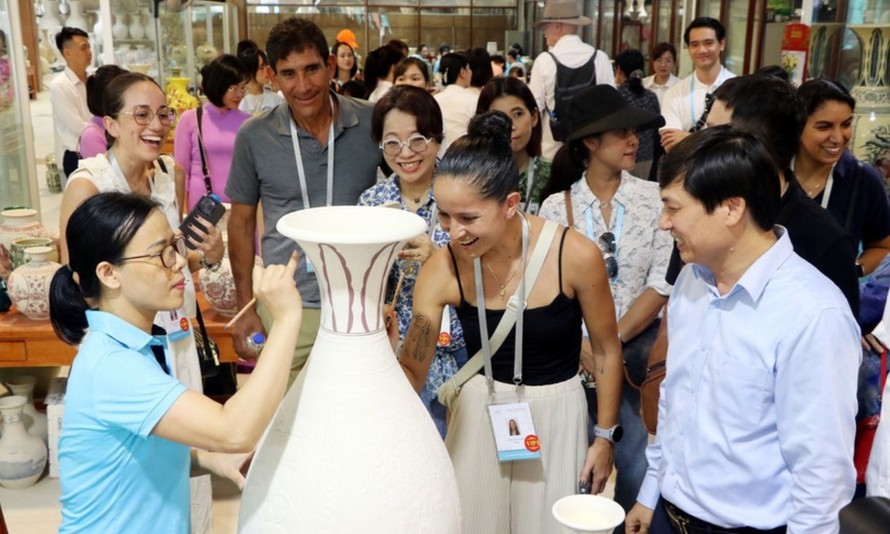 Các vị khách quốc tế trải nghiệm vẽ hoa văn lên các bình gốm thô. Ảnh: Mạnh Tú