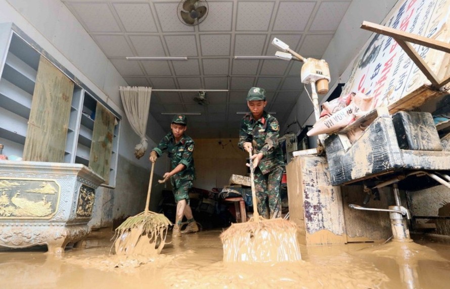 Lực lượng quân đội hỗ trợ người dân tổ 4, xã Sông Mã, Sơn La, thu gom bùn đất, cành cây, rác bị tràn về trong đợt lũ vừa qua. Ảnh: Quang Quyết