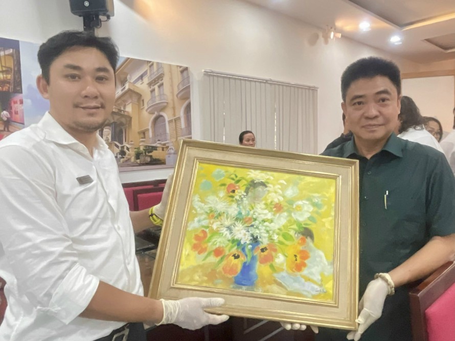 PGS.TS Lâm Nhân (phải) đại diện ông bà Lê Tất Luyện - Thụy Khuê và ông Trần Minh Công, Phó Giám đốc phụ trách Bảo tàng Mỹ thuật TPHCM nâng niu một tác phẩm của danh họa Lê Phổ