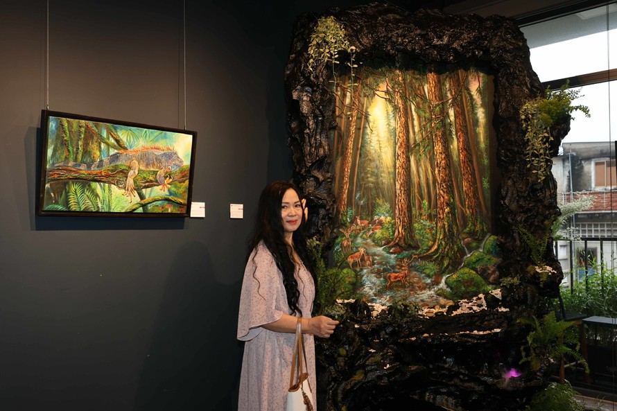 Họa sĩ Trương Kim bên một tác phẩm tại triển lãm. Ảnh: TRÀ TRƯƠNG