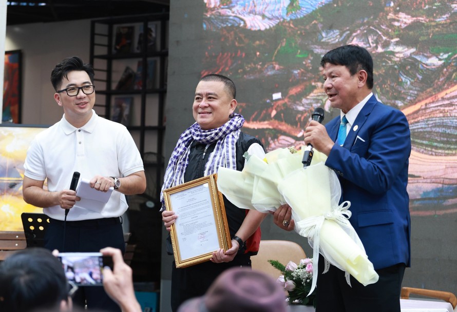 Chủ tịch Hội Nhiếp ảnh TPHCM Đoàn Hoài Trung (phải) chúc mừng NSNA Hồ Vũ (giữa) tại buổi khai mạc triển lãm “Góc nhìn nửa thế kỷ” ngày 21/6 tại Đường Sách TPHCM