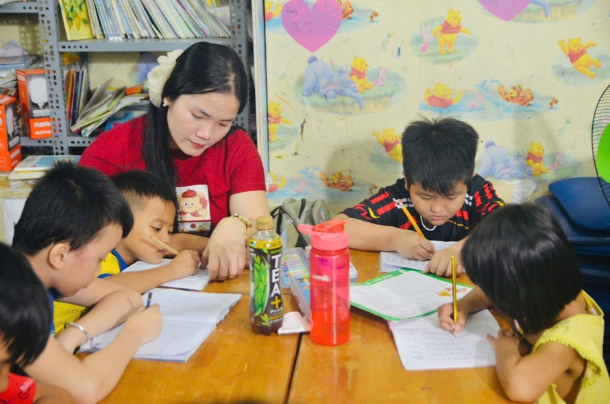 Chị Danh Thị Thanh Thúy (áo đỏ) đang dạy các em nhỏ học chữ.