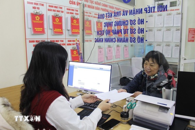 Cán bộ phường hướng dẫn người dân làm thủ tục hành chính. Ảnh: Nguyễn Thắng/TTXVN.