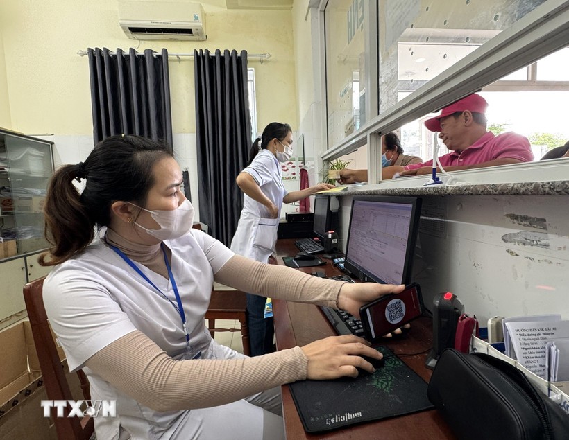 Nhân viên y tế quét mã lấy số và đăng ký khám bệnh tại các ki-ốt phát số tự động. Ảnh: Đinh Hương/TTXVN.