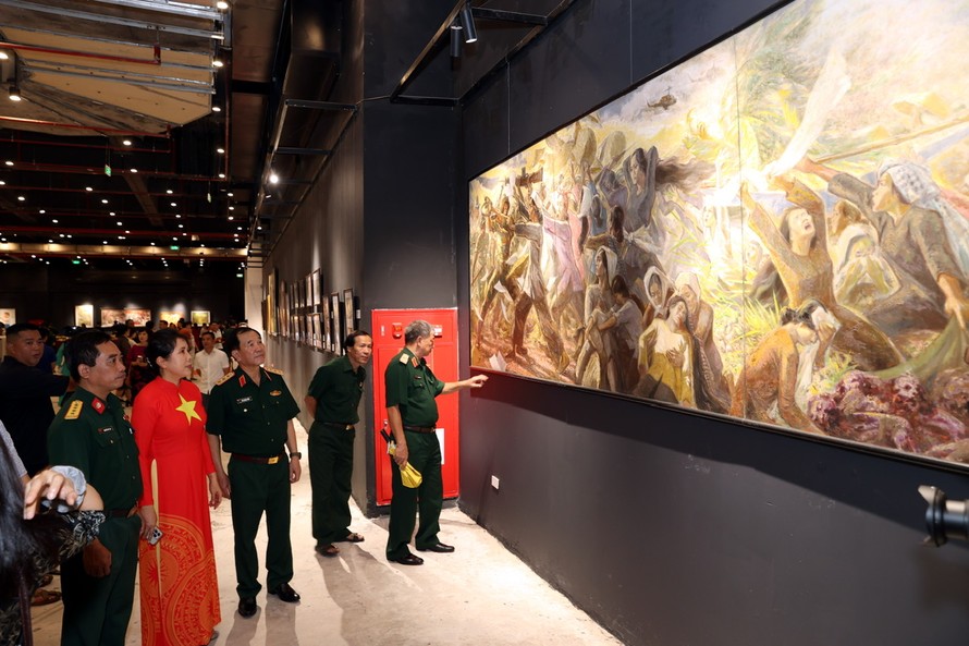 Các đại biểu Bộ Quốc phòng ngắm tác phẩm sơn dầu "Đội quân tóc dài" của hoạ sĩ Lê Lam.