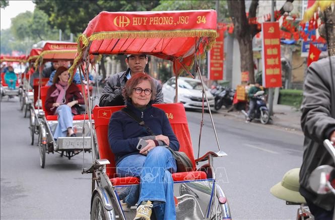 Du khách nước ngoài thích thú với khí hậu mát lạnh và trải nghiệm đi xích lô giữa không gian Thủ đô yên bình. Ảnh: Phan Phương/TTXVN.