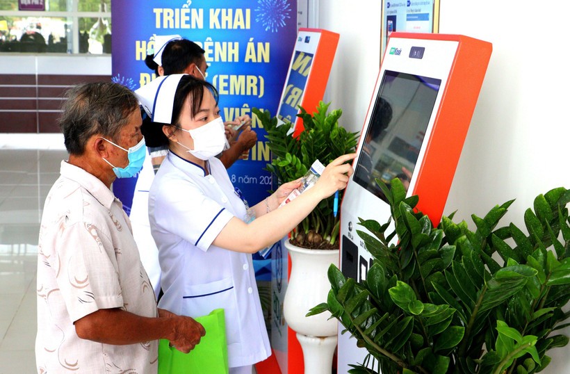 Nhân viên y tế hướng dẫn người dân đăng ký khám bệnh qua hệ thống kios tự động tại Bệnh viện Đa khoa Trà Vinh, tỉnh Vĩnh Long. Ảnh: TTXVN.