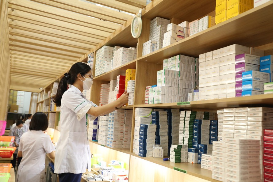 Nhân viên y tế cấp phát thuốc bảo hiểm y tế cho người bệnh.