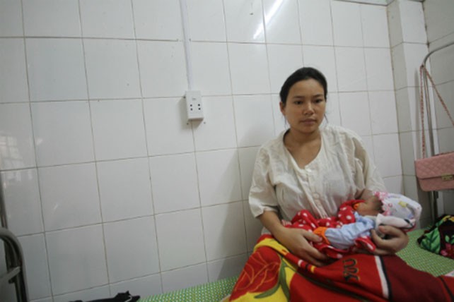 Chị Thành cùng cô con gái vừa chào đời mang ơn người anh em họ đã xả thân cứu mình. Ảnh: Nguyễn Đông.