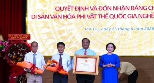 Bà Trần Thị Đoan Quang, Giám đốc Bảo tàng tỉnh Tây Ninh trao Bằng chứng nhận Di sản Văn hóa Phi vật thể Quốc gia đối với Nghề làm trống Bình An cho lãnh đạo Ủy ban Nhân dân xã Tân Trụ. (Ảnh: Thanh Bình/TTXVN)