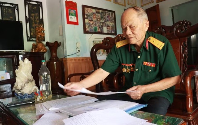 Cựu chiến binh Nguyễn Thanh Bình cẩn thận ghi chép, lưu giữ thông tin tên, ngày hy sinh, đơn vị chiến đấu, quê quán, thân nhân các liệt sỹ. (Ảnh: Tường Vi/TTXVN)