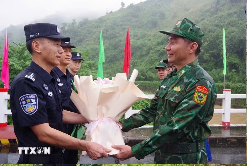 Đại diện chỉ huy trưởng tuần tra hai bên tặng hoa cho nhau tại vạch phân định cầu hữu nghị biên giới Việt-Trung. (Ảnh: TTXVN phát)